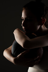 Teenage girl with basketball. Side lit studio portrait against dark background..