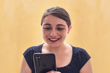 Mujer latina mirando sonriente sus redes sociales en el celular