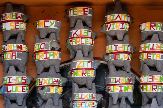 Molcajetes de piedra volc&aacute;nica con nombres de personas grabados apilados para la venta