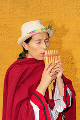 closeup of latin american peasant woman with hat and rustic yellow wall in the background