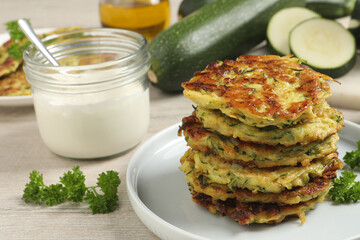 Delicious zucchini fritters served on white wooden table, closeup