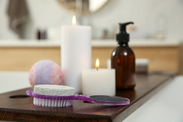 Fototapeta na wymiar Pedicure tool with pumice stone and foot file near burning candles on wooden caddy in bathroom