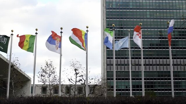 Flags in front of United Nations in New York City. Slow motion flags flying in the wind. Sierra Leone flag, Indonesia , Seychelles and United Nations Flag in the background