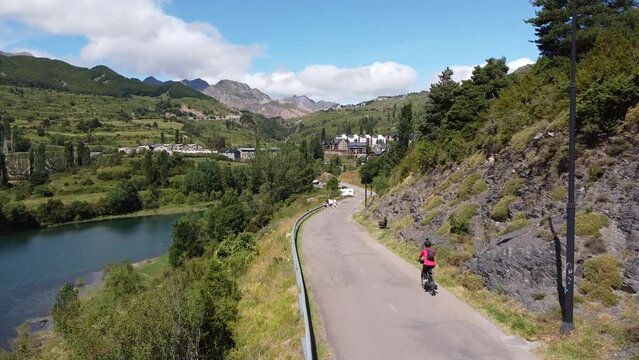 Sallent de Gallego at Tena Valley, Huesca, Aragon, Spanish Pyrenees, Spain - Aerial Drone View of a Tourist Girl Mountainbiking around Lake Embalse de Bubal