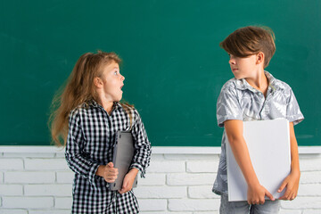School amazed siblings children hold book with surprising expression against blackboard. School kids friends.