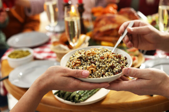 Woman giving bowl of traditional Christmas Slavic dish kutia to man at festive dinner, closeup - Powered by Adobe