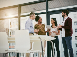 Discussing the status of business. Shot of a group of colleagues having a meeting in a modern...