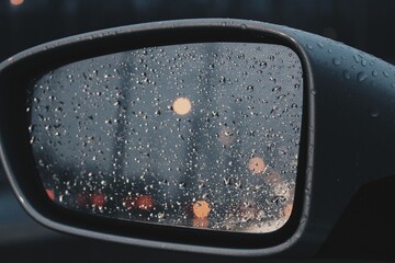 Close up view of a side view mirror with rain droplets 