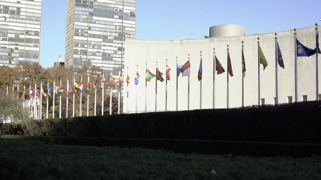Different flags in front of United Nations in USA. International flags in Slomo. Security council of the United Nations concept