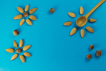 Almonds and hazelnuts in a shell, wooden spoon on a blue background