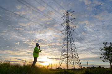 Engineer inspecting high voltage tower with radio,Engineer inspecting high voltage tower