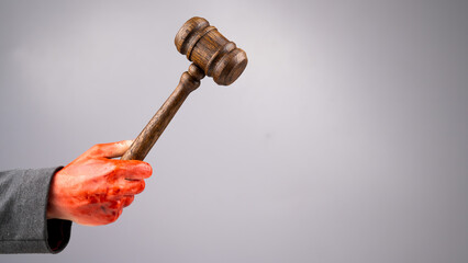 A female judge holds a gavel in a bloody hand on a white background. Copy space. 