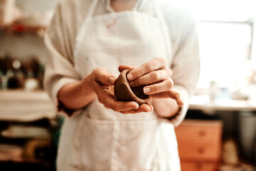 I create objects from earthenware materials. Cropped shot of a woman shaping a clay pot in her workshop.