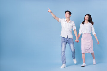 Full length image of young Asian couple on blue background