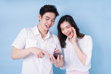 Image of young Asian couple using smartphone on blue background