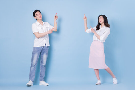 Full length image of young Asian couple on blue background