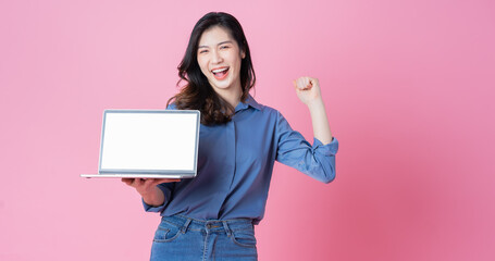 Young Asian businesswoman using laptop on pink background