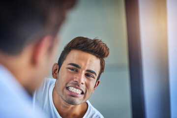 Teeth in mint condition. Shot of a handsome young man admiring his freshly brushed teeth in the...
