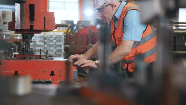 Engineer or operator wearing a safety suit working bending metal sheet by sheet press bending machine in workshop, Worker in factory at metal folding machine putting work piece at factory industry