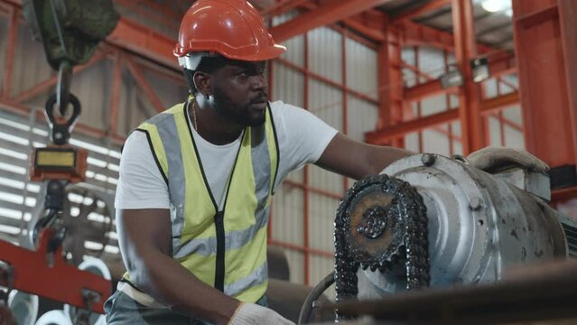 Engineer or operator wearing a safety suit maintaining machine in the industrial factory, service technicain worker operating tighten the nut repair machinery at metal sheet factory