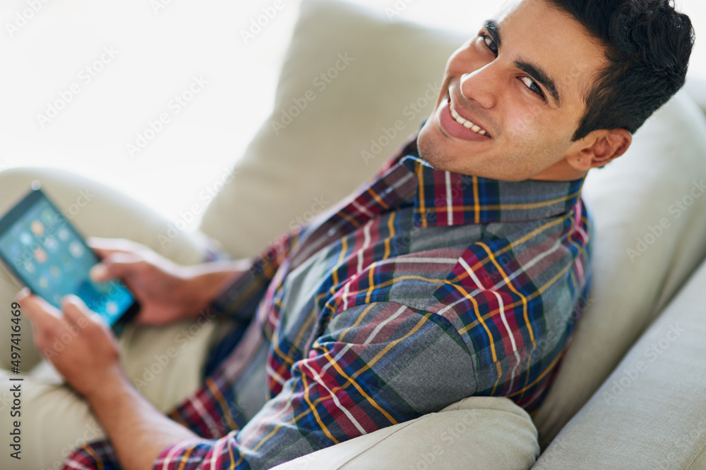 Poster theres nothing more convenient than a tablet. portrait of a handsome young man using his tablet whil