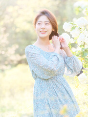 Portrait of elegant Chinese girl in dress enjoy carefree time in forest park in sunny day. Outdoor fashion portrait of glamour young Chinese cheerful stylish woman.