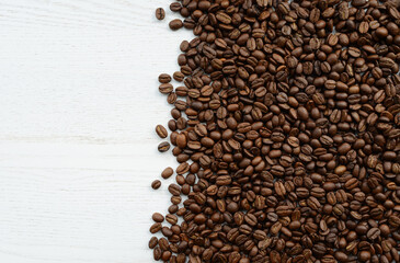 Coffee beans on a white wooden table. Roasted coffee beans on a white background, top view, copy space