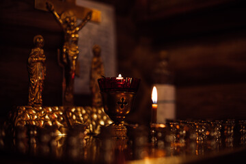 Close-up of candles on golden stand with candlesticks on altar in front of crucifixion of Jesus,...