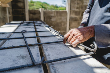 Hands of a Latino male worker preparing the construction rods. 