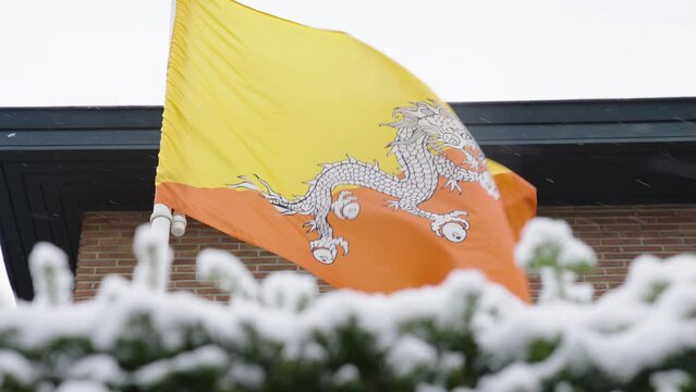 Close up slow motion shot of Bhutan flag waving with the wind in snowy city center