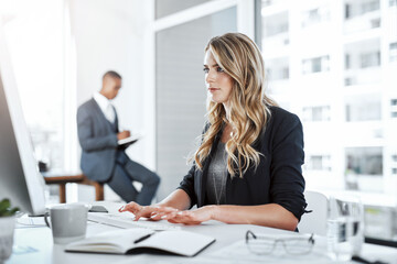 Theres no off button to her productivity. Shot of a young businesswoman using a computer at her desk in a modern office.