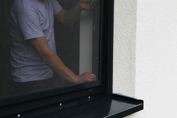 Handwerker montiert ein Fliegengitter an einem Fenster