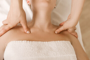 Massage and body care. A young woman receives a relaxing and toning facial and neck massage at the spa.
