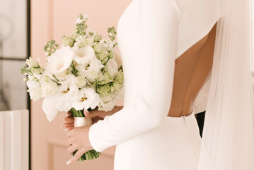 A luxurious wedding bouquet with white roses in the hands of the bride