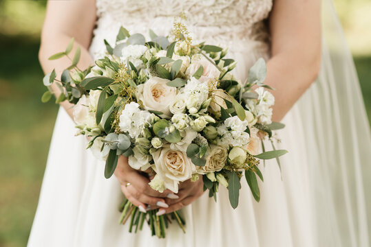 A luxurious wedding bouquet with white roses in the hands of the bride
