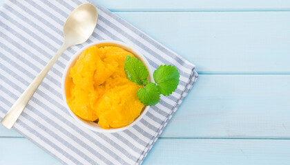 Portion of mango ice cream garnished with a sprig of mint