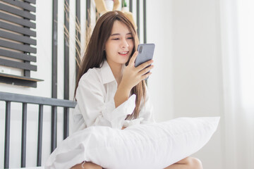 Portrait young smile happy beautiful asian woman relax bedroom. woman relax use smartphone gadget online shopping work from home.