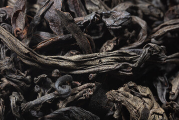 Dried black tea leaves as background.