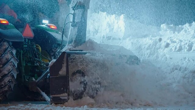 Snow plow blower truck cleaning thick snow after blizzard storm from road at night