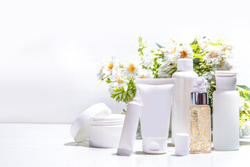 Foraged and wild-harvested beauty, Cosmetic skincare products on white background with wild grown flowers. Set white jars, tubes, droppers, bottles. Spa, daily organic natural skin care routine
