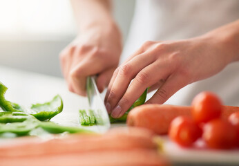 Preparing a wholesome meal filled with organic goodness. Closeup shot of a young woman chopping vegetables in the kitchen.
