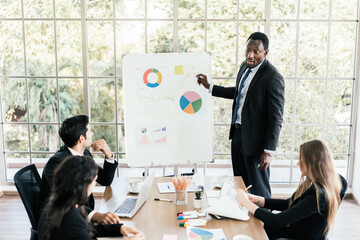 African businessman presents and listens to opinions at a business group meeting, Discussion about the new business plan in the office. Businesspeople of various nationalities.