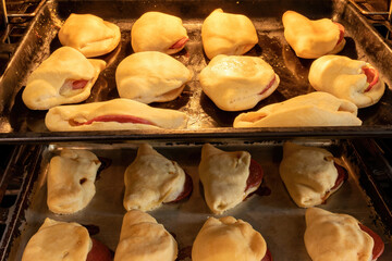 Sausage in dough baked in the oven. Hot pies with sausage in the oven.