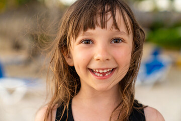 A close-up portrait of a pretty 6 year old girl with one missing tooth. Funny toothless smile