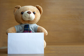Brown teddy bears and white blank paper on brown wooden background. Birthday or anniversary greeting card concept.