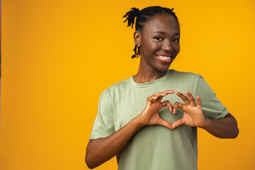 Young african american woman smiling and showing a heart shape with hands