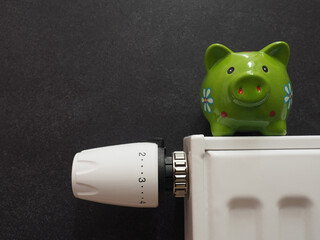 Save energy concept, radiator and heating thermostat with a piggy bank, space for your text, Stop...