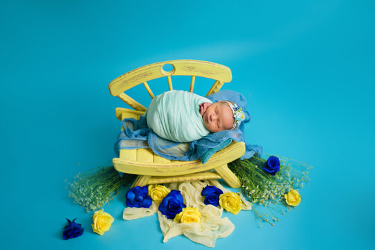 Ukrainian newborn in the studio patriotic blue yellow colors during the war in Ukraine 2022. A little baby, girl sleeps on a chair 
