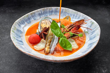 Bouillabaisse soup with seafood on a plate, on a dark background