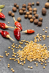 Mustard seeds, dry red pepper pods and allspice on table.